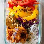 Chicken Satay Skewers on raw vegetables and rice noodles with peanut sauce