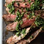 Sliced Flank Steak with Chimichurri on a cutting board