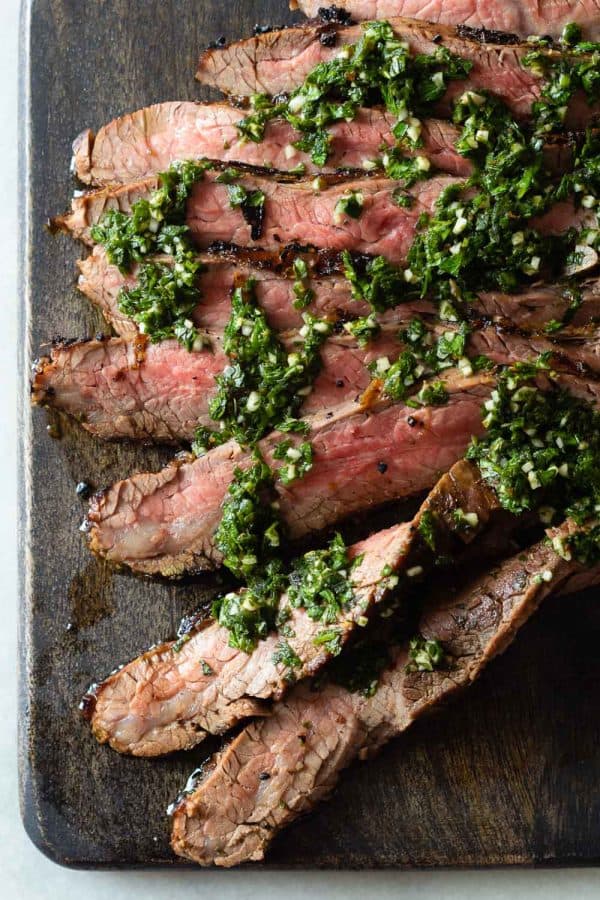 Sliced Flank Steak with Chimichurri on a cutting board