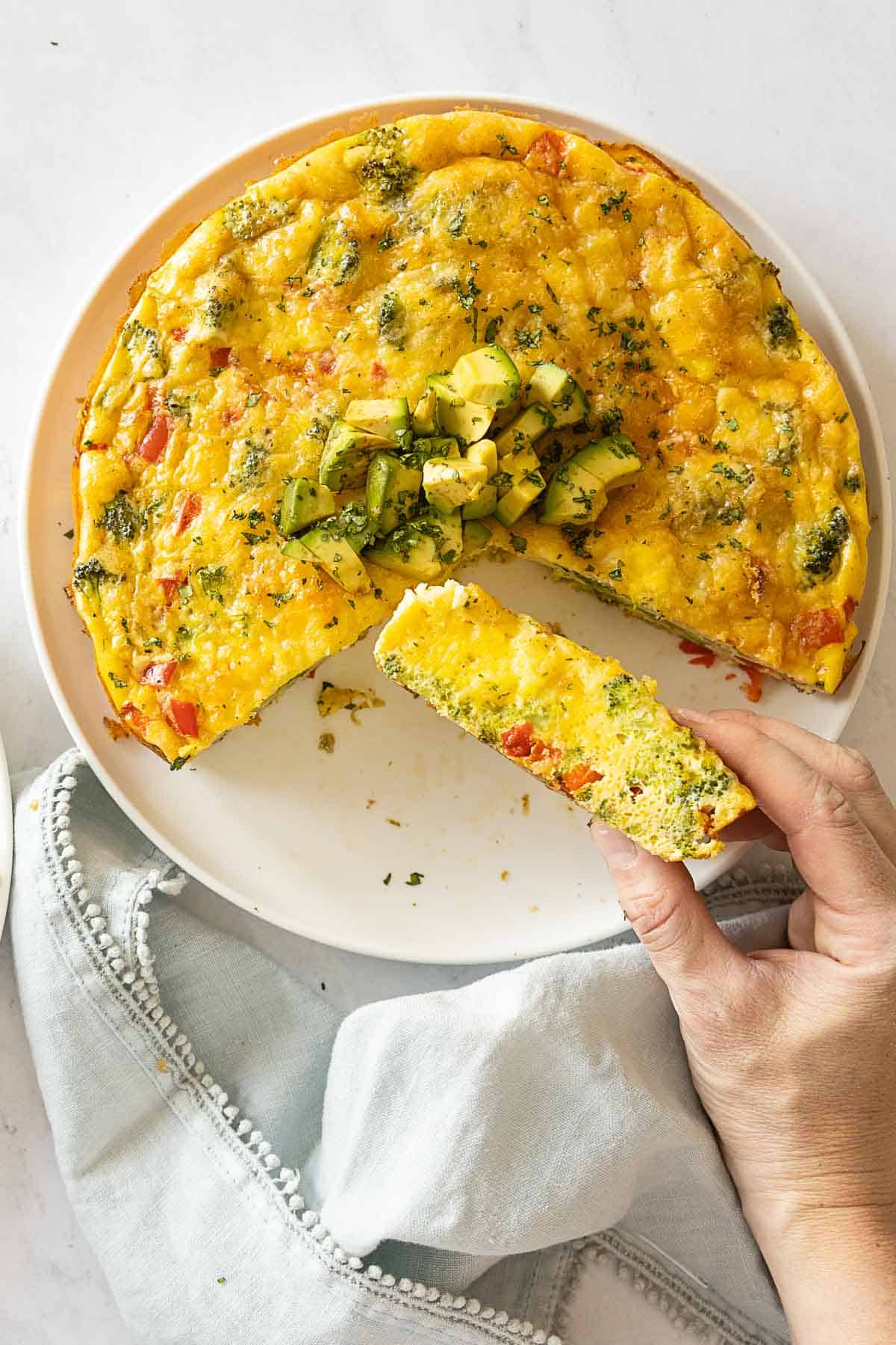 Vegetabel Frittata with 1/4 cup out and one piece in hand to show texture.