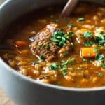 closeup of beef and barley soup in a black bowl