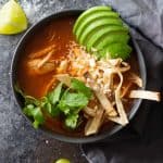 Instant Pot Chicken Tortilla Soup in a black bowl topped with avocado tortilla strips and cilantro