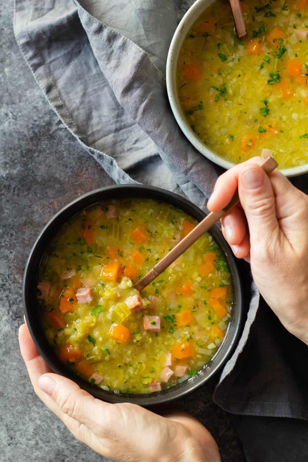 Instant Pot Split Pea Soup in two bowls and two hands holding bowl and spoon