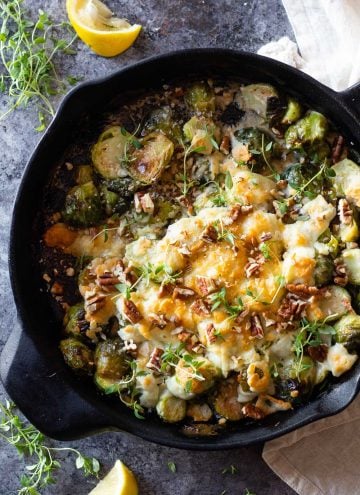 Brussels Sprouts in a black cast iron pan with melted cheese on top