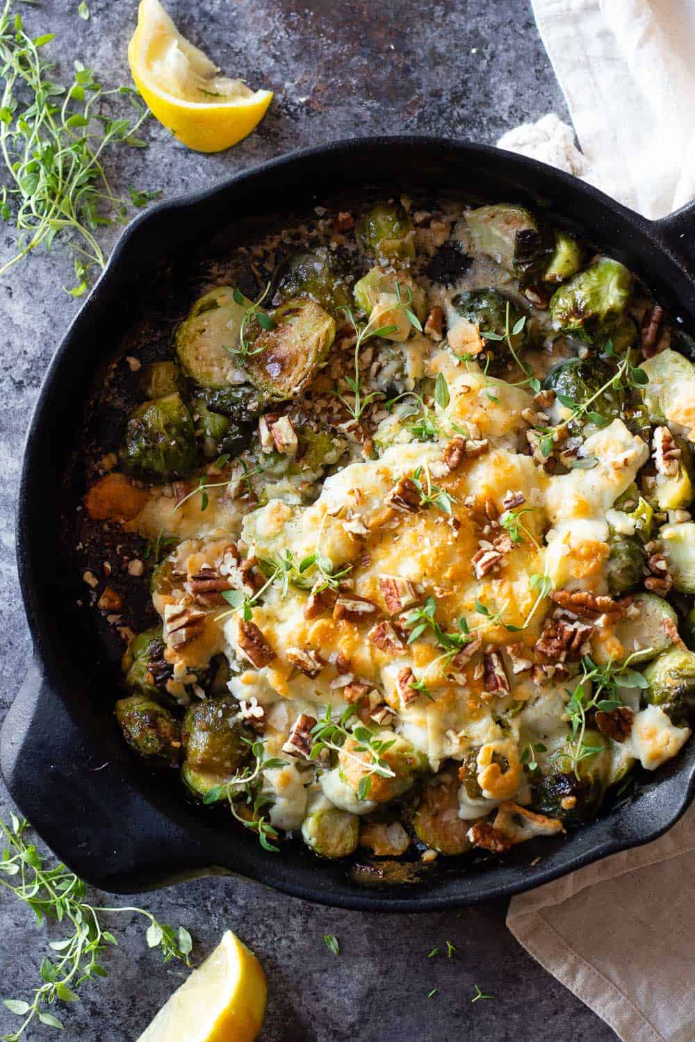 Brussels Sprouts in a black cast iron pan with melted cheese on top
