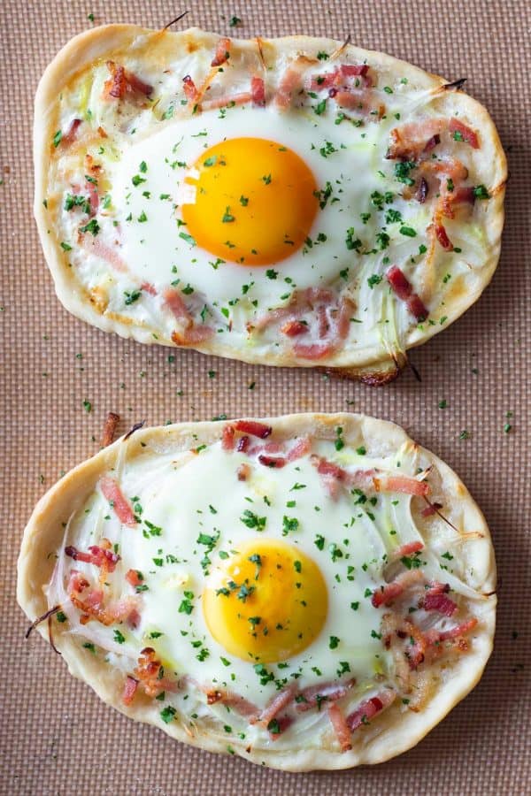 Two breakfast pizzas on a baking sheet