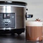 Mexican spiced hot chocolate in a cup in front of a Slow-Cooker