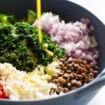 pouring lemon dressing over lentil salad