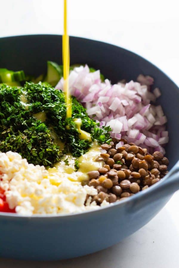 pouring lemon dressing over lentil salad