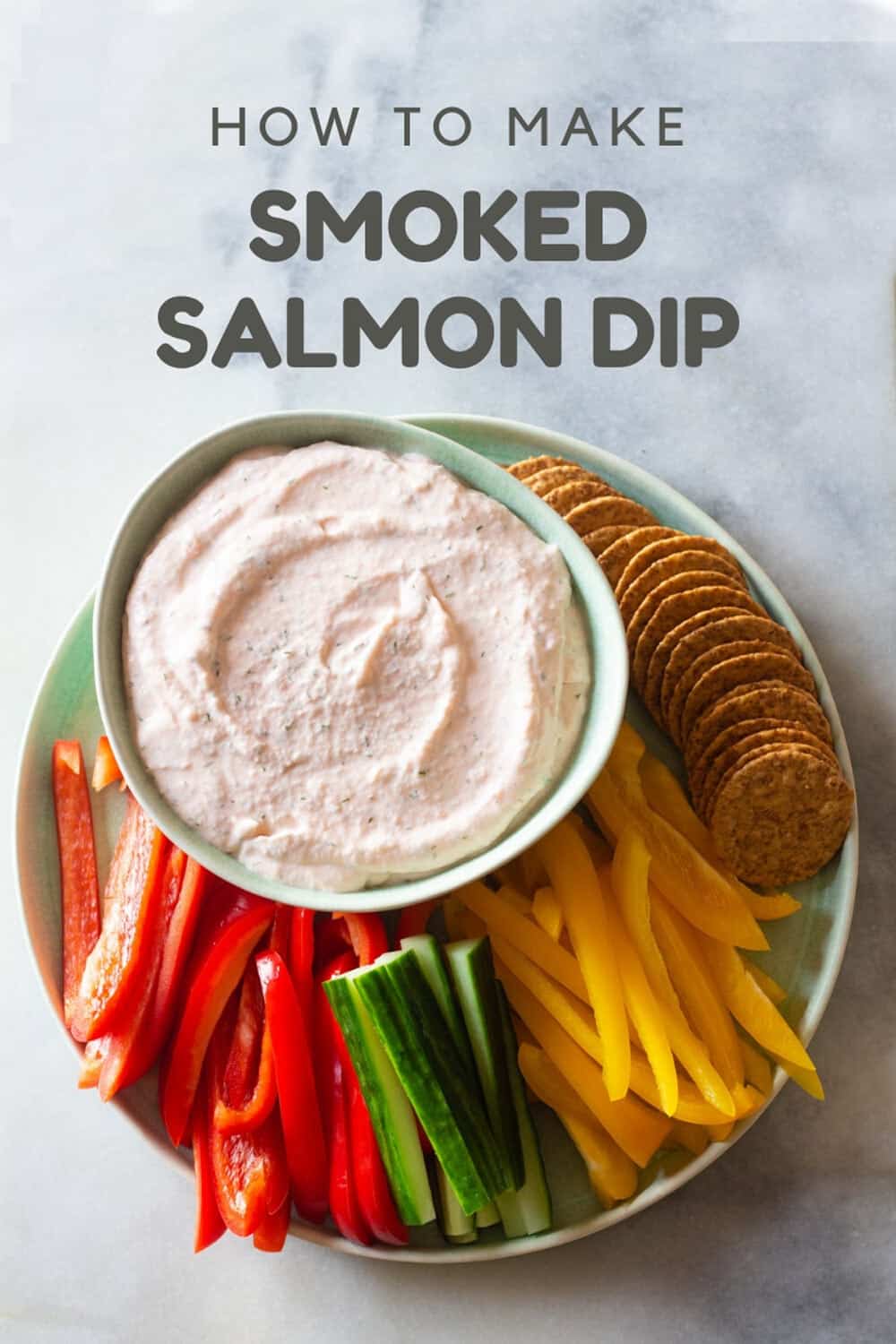Smoked salmon dip with crackers and raw vegetables arranged on a plate