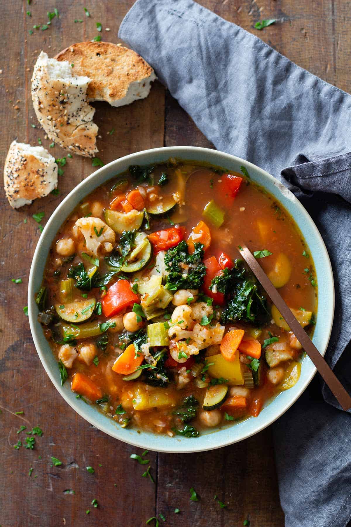 Vegetable Soup made in the instant pot in a blue bowl on a wooden table and bread and a napkin next to the bowl