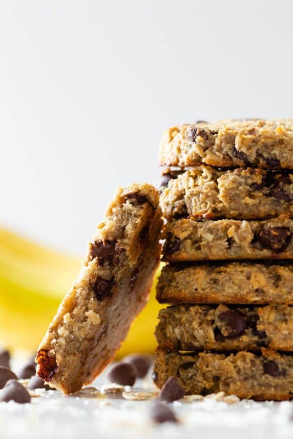 Banana Oatmeal Cookies with chocolate chips stacked on top of each other with one cookie bitten to the side.