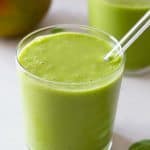 Spinach Mango Smoothie in a glass with glass straw