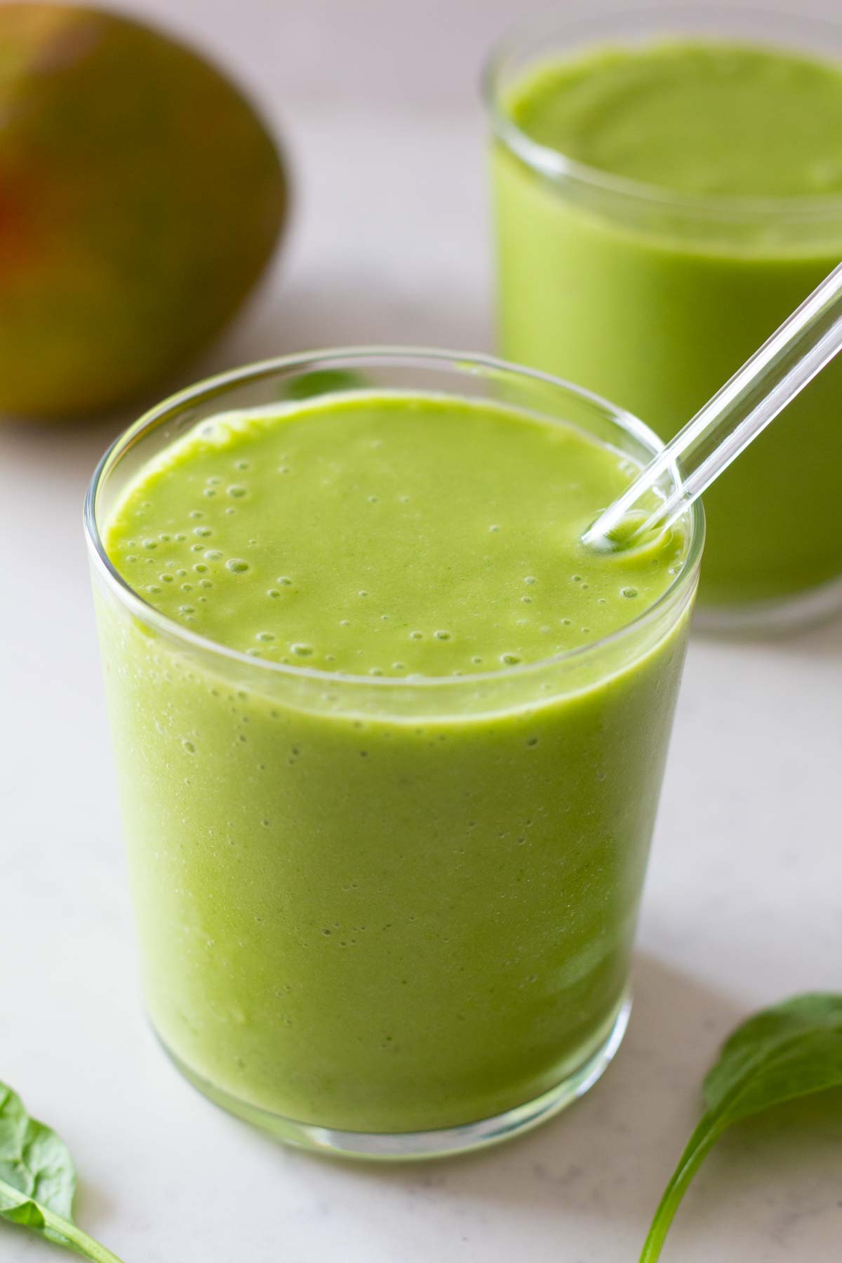 Spinach Mango Smoothie in a glass with glass straw