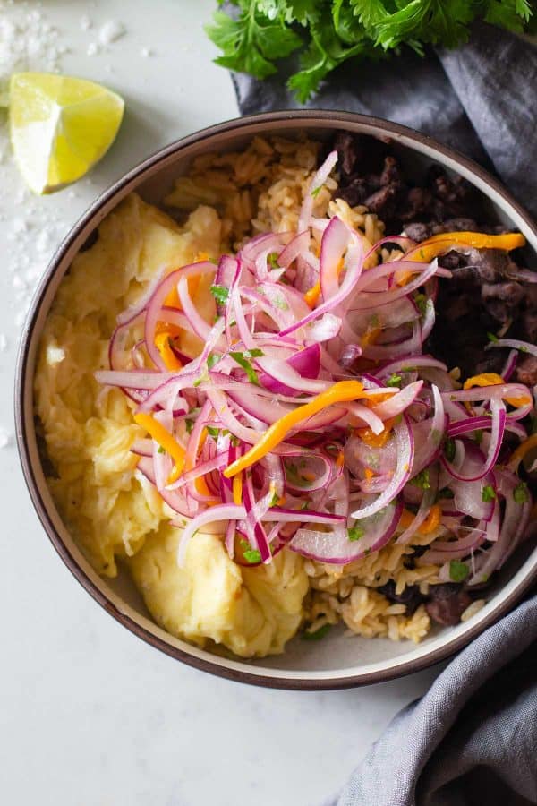 Black beans, rice, and scrambled eggs topped with salsa criolla.