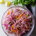 sliced red onion, aji amarillo pepper and cilantro (a.k.a. as salsa criolla) in a mixing bowl.