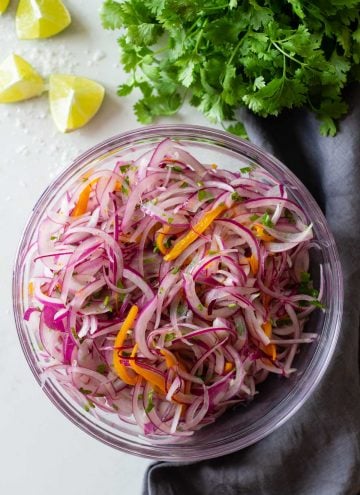 sliced red onion, aji amarillo pepper and cilantro (a.k.a. as salsa criolla) in a mixing bowl.