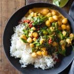 Bowl with white rice and coconut chickpea curry with baby spinach.