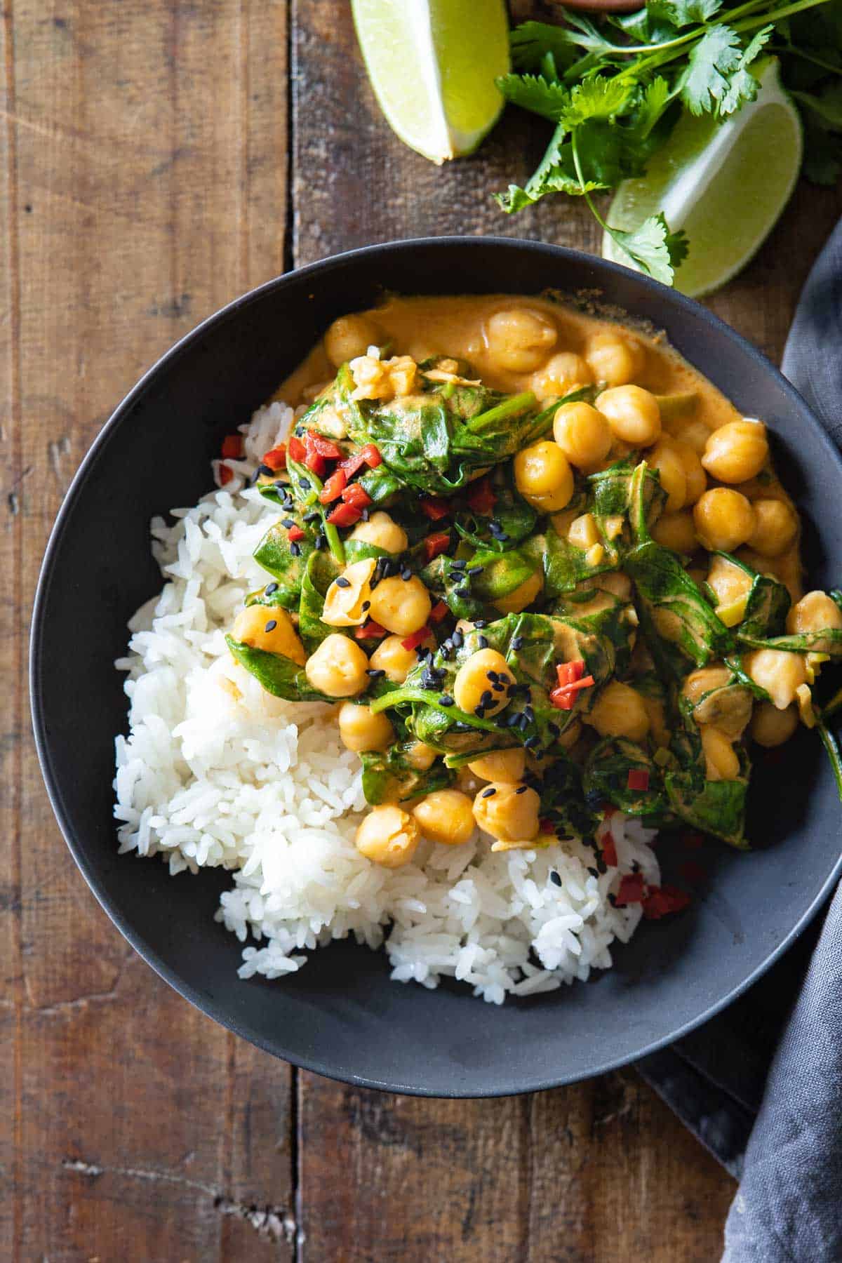 Bowl with white rice and coconut chickpea curry with baby spinach.