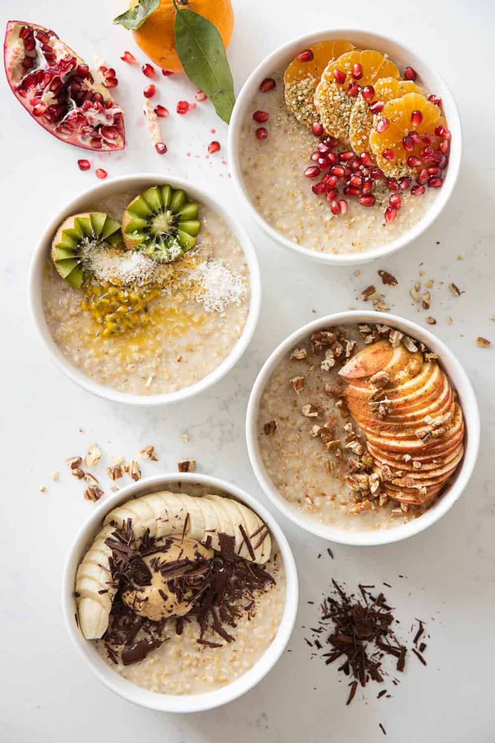 4 bowls of creamy steel cut oats topped with fall/winter fruit, nuts, and seeds.