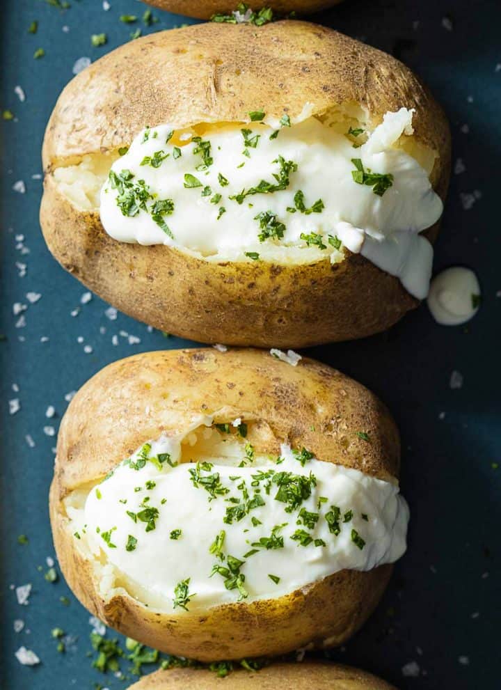 Baked Potatoes topped with sour cream and chopped parsley.