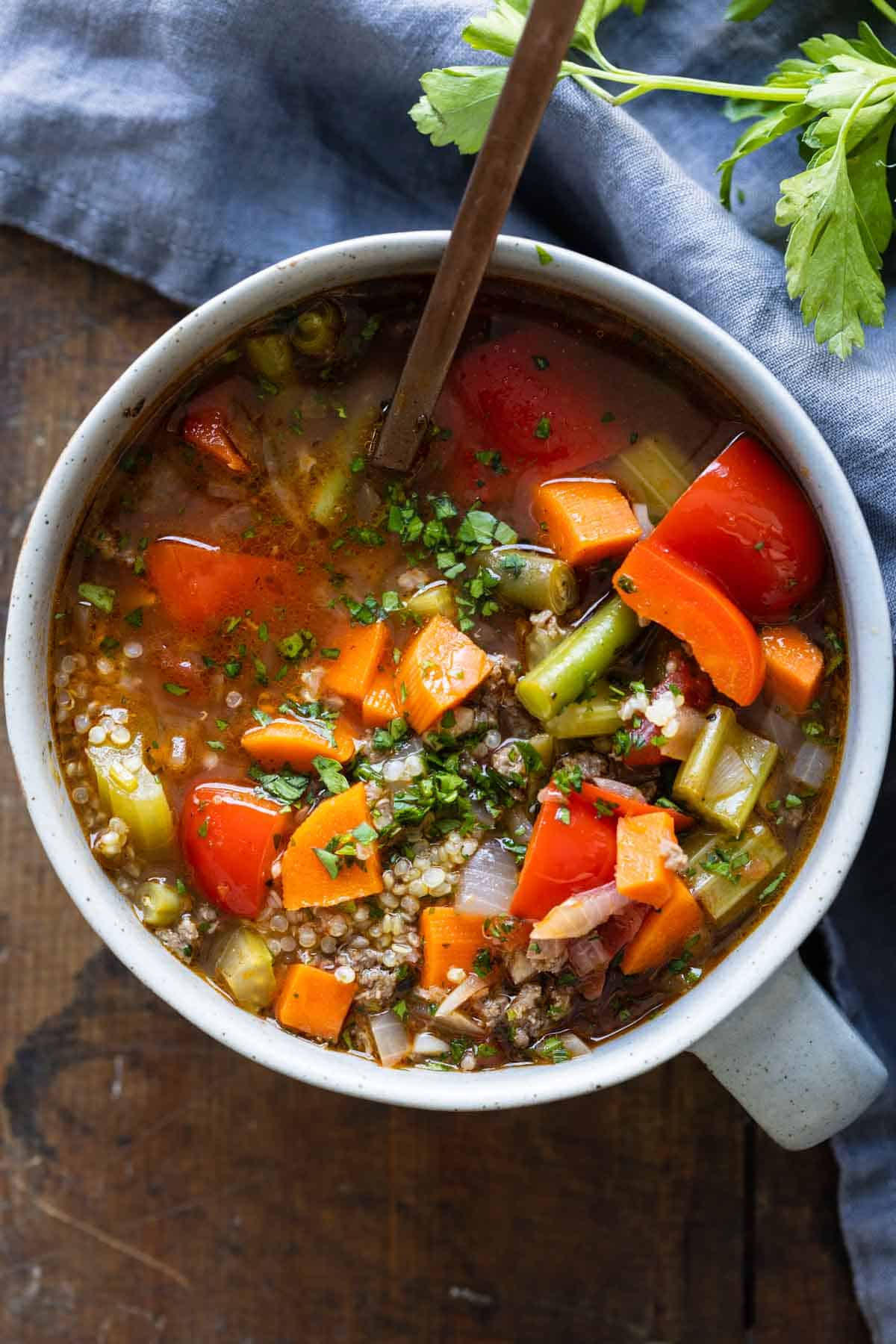 sou with colorful vegetables and ground beef in a small grey bowl.