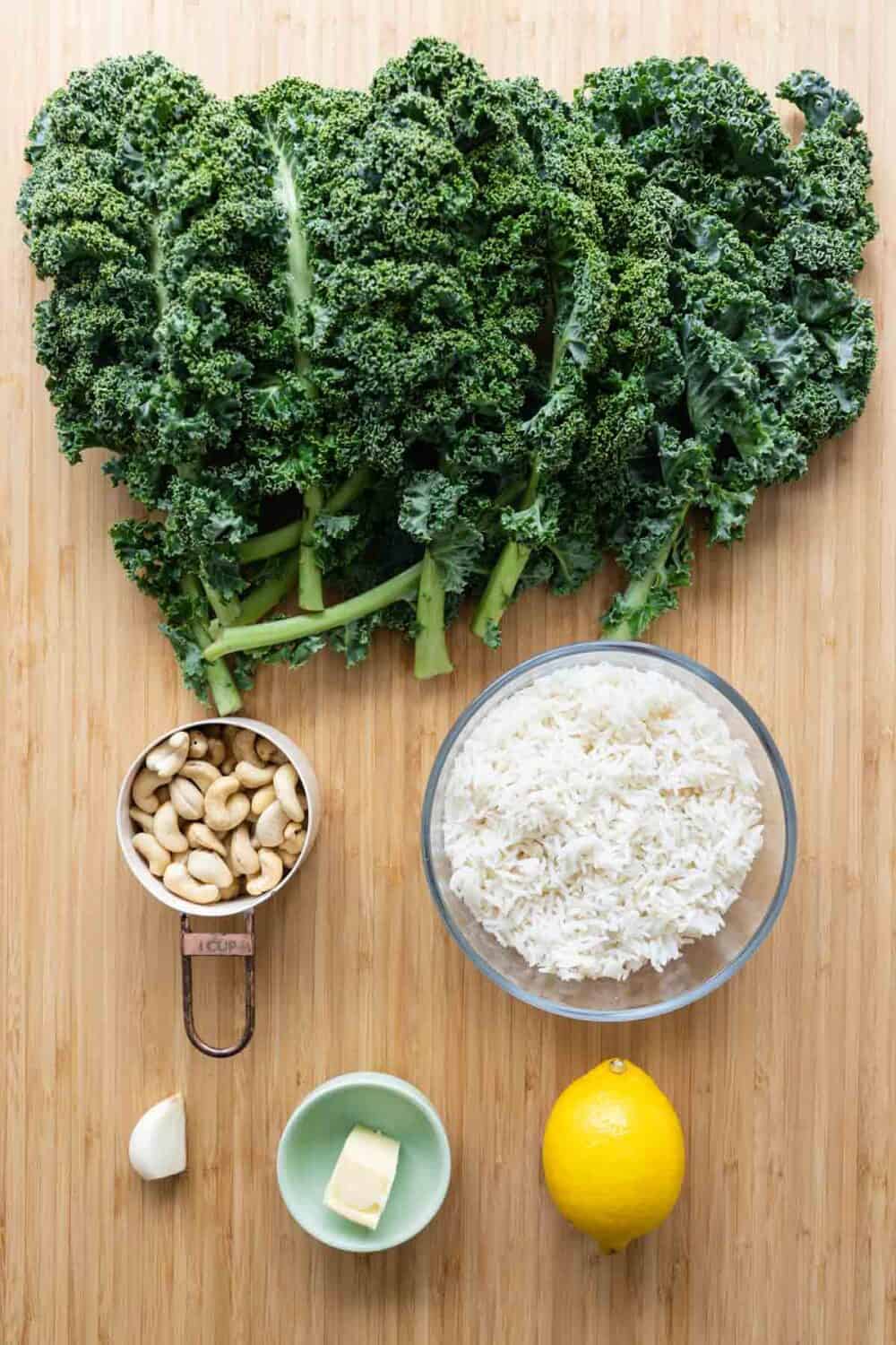 kale, white rice, cashews, garlic, butter, and lemon on a kitchen counter.