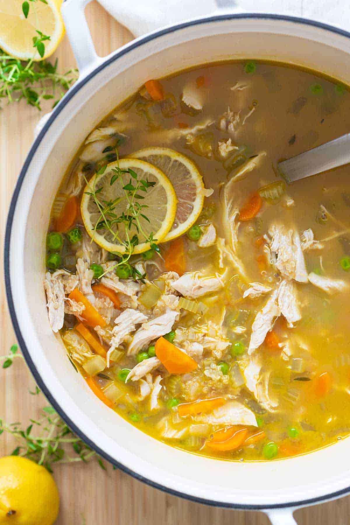 Chicken Soup in a large white pot with two lemon slices placed on top.