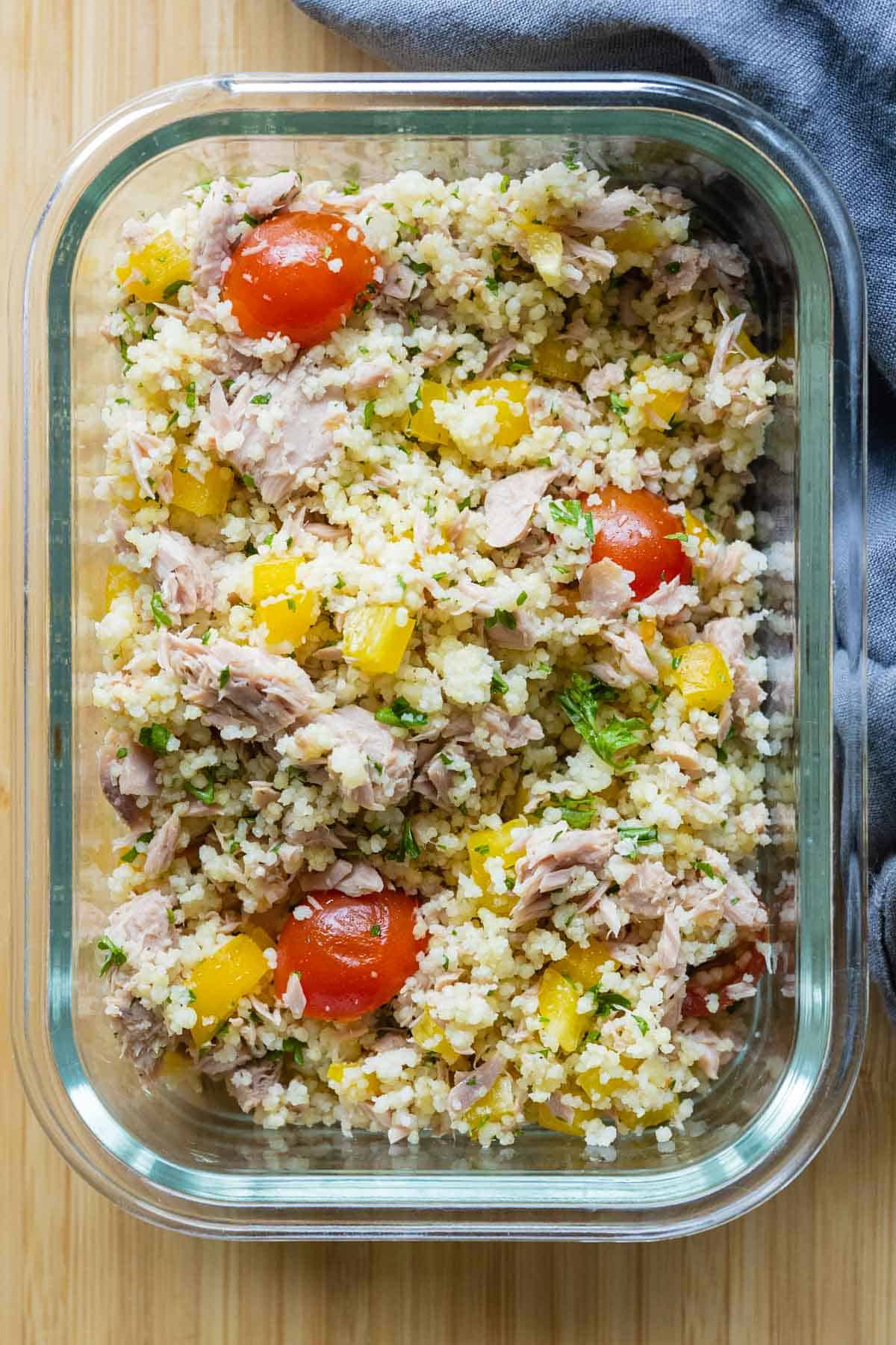 Glass container with a mix of couscous, tuna, and vegetables.