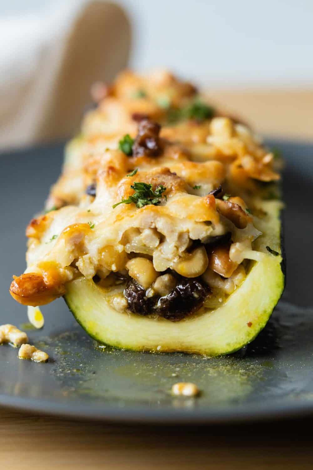 Cut-up stuffed zucchini boat on a gray plate.