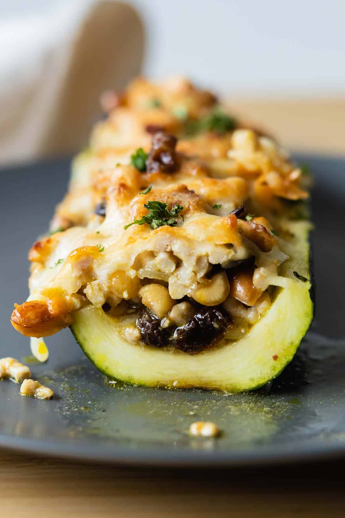 Cut-up stuffed zucchini boat on a gray plate.