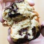 hands pulling apart a healthy banana muffin showing inside texture and dark chocolate bits.