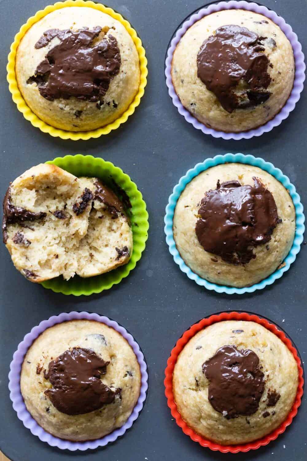 6 muffins with chocolate on top in colorful silicone muffin liners.