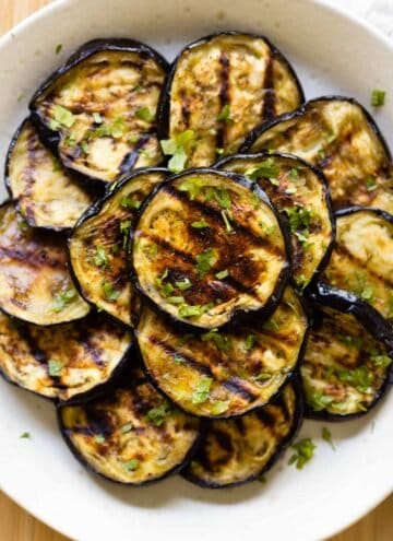 Grilled eggplant rounds stacked on a plate.