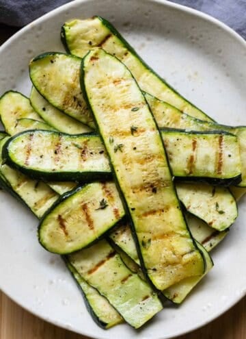 Thinly sliced grilled zucchini on a plate.