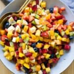 Fruit Salad mixed up and in a large grey bowl.