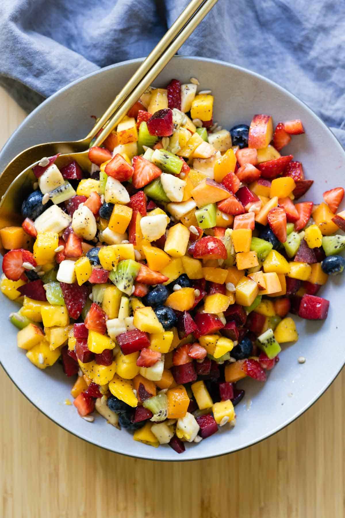 Fruit Salad mixed up and in a large grey bowl.