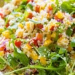 Mixed up couscous salad with arugula in a salad bowl.