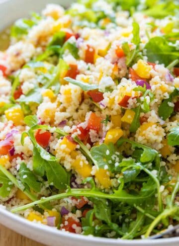Mixed up couscous salad with arugula in a salad bowl.