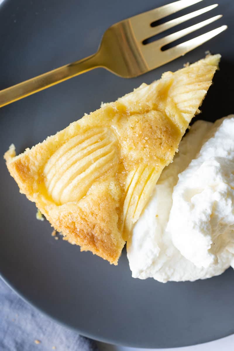 A piece of German Apple Cake with whipped cream on the side.