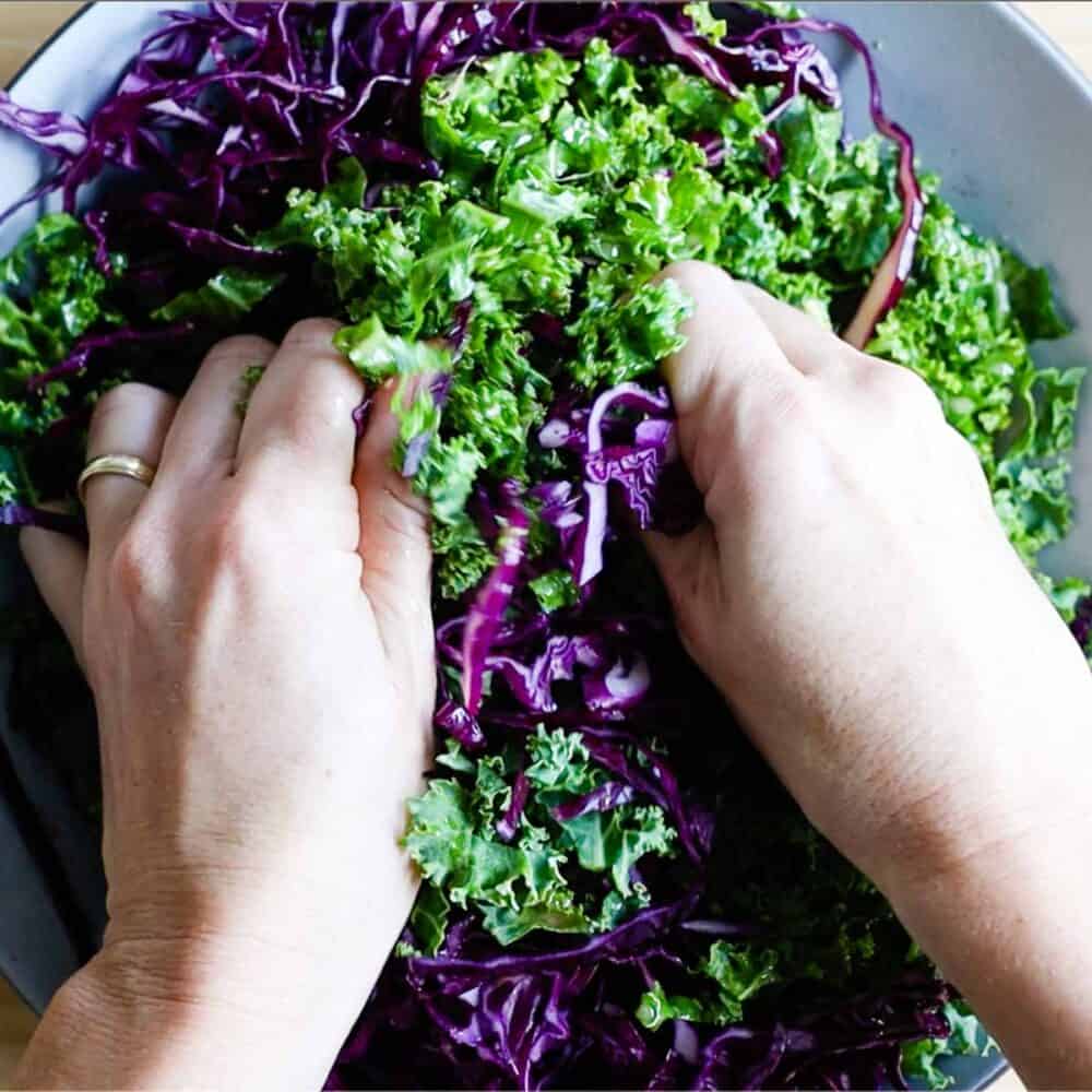 Massaging kale with hands.