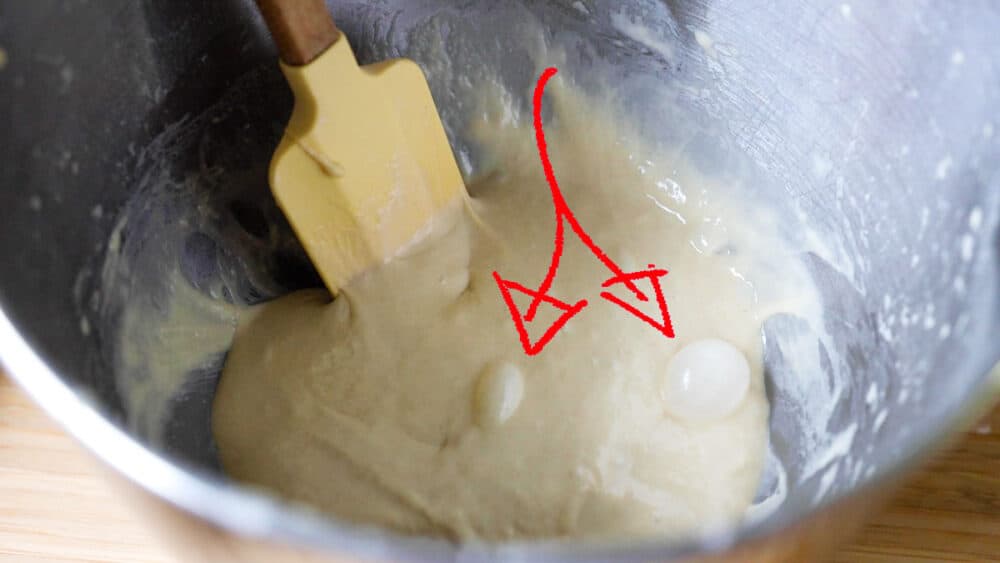 Air bubbles in german spaetzle dough with an arrow pointing on them.