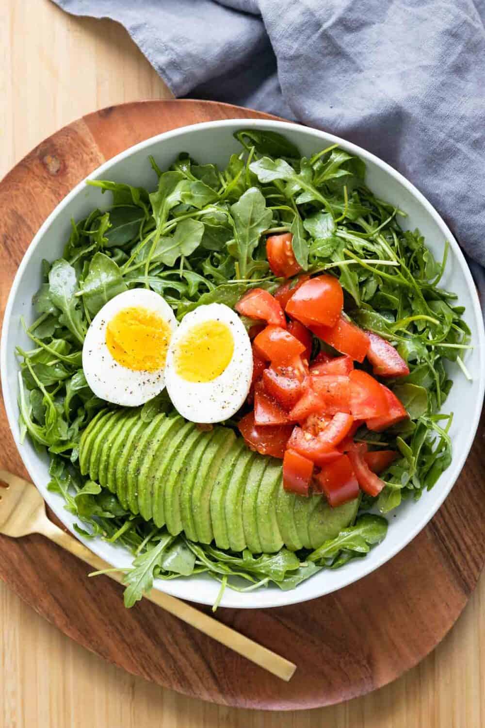 Breakfast salad made of arugula, tomato, avocado, and hard-boiled egg.