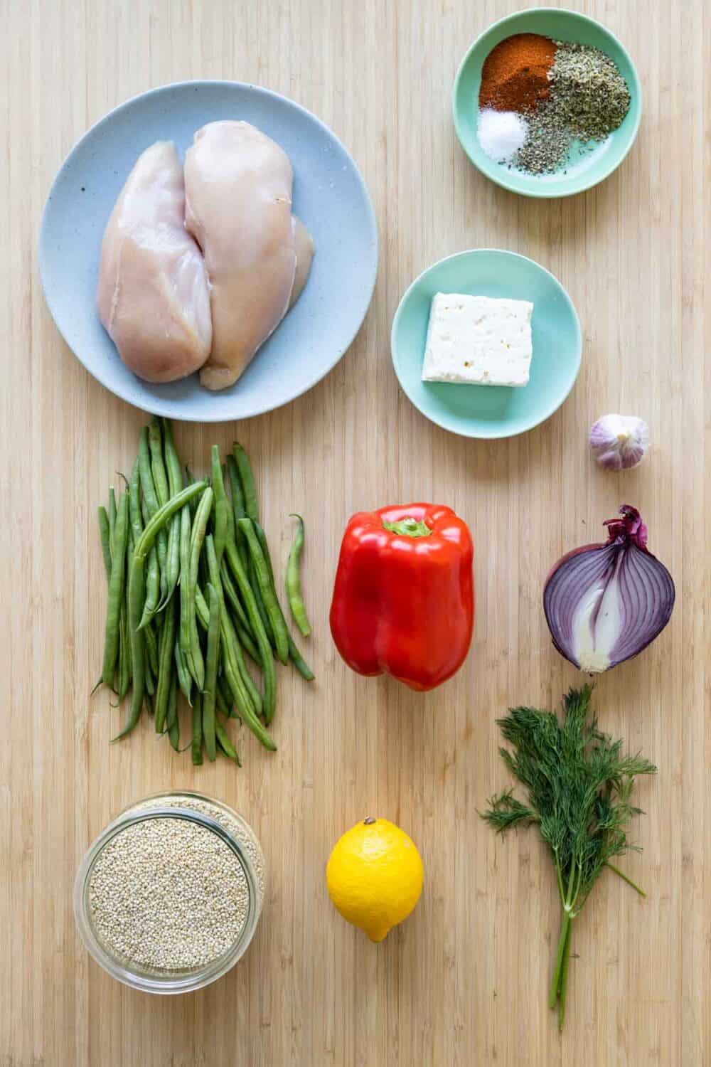 Ingredients for chicken quinoa bowl laid out on a kitchen counter.