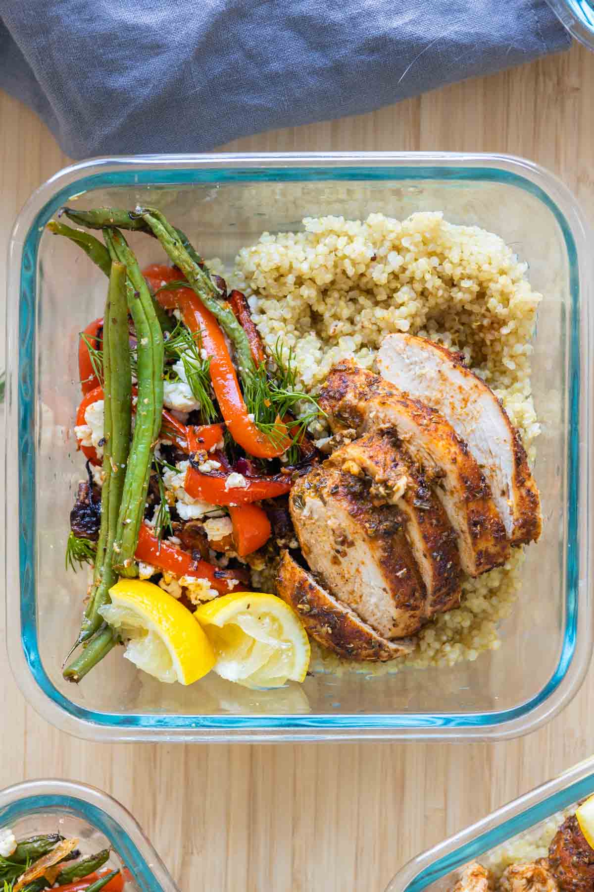 Square bowl with chicken, quinoa, and roasted vegetables.