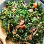 Kale Quinoa Salad in a grey salad bowl with wooden spoons.