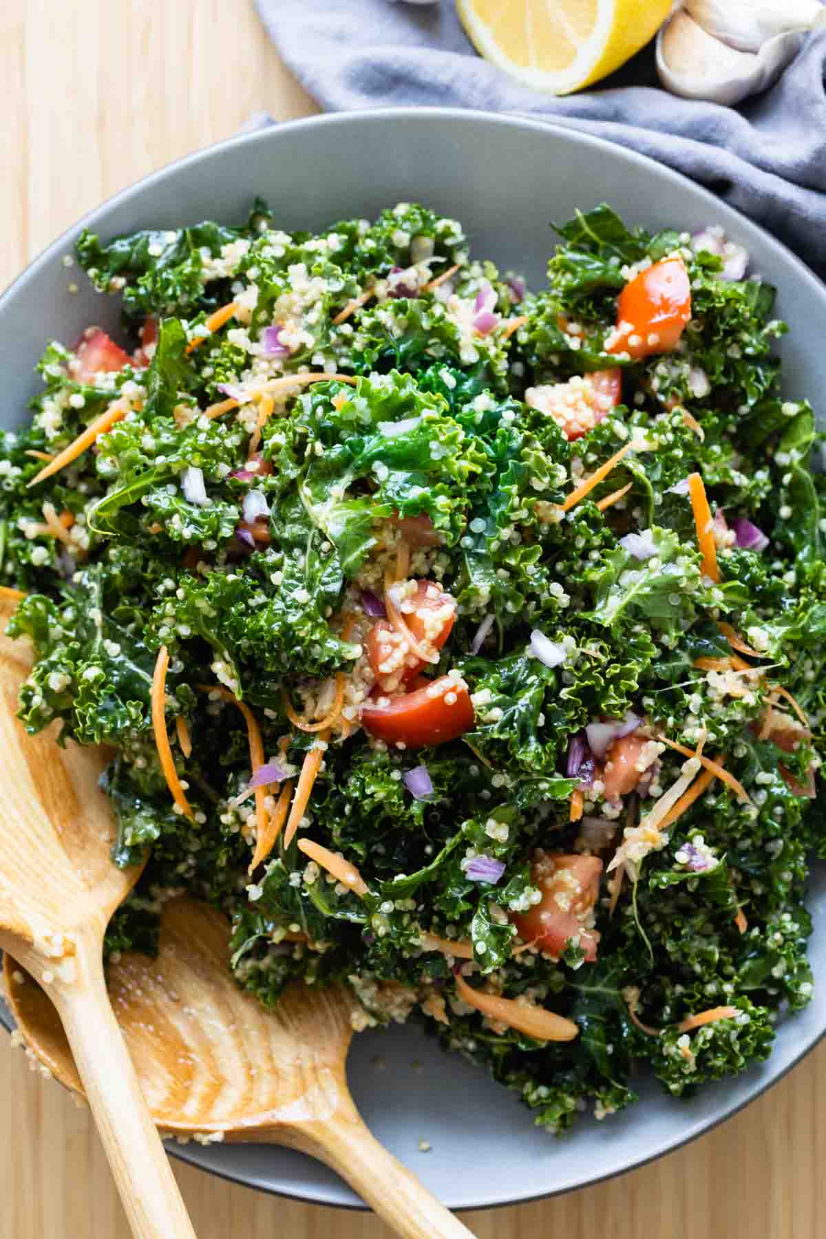 Kale Quinoa Salad in a grey salad bowl with wooden spoons.