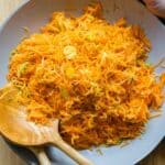 Grated Carrot Salad in a large grey salad bowl with two wooden spoons.