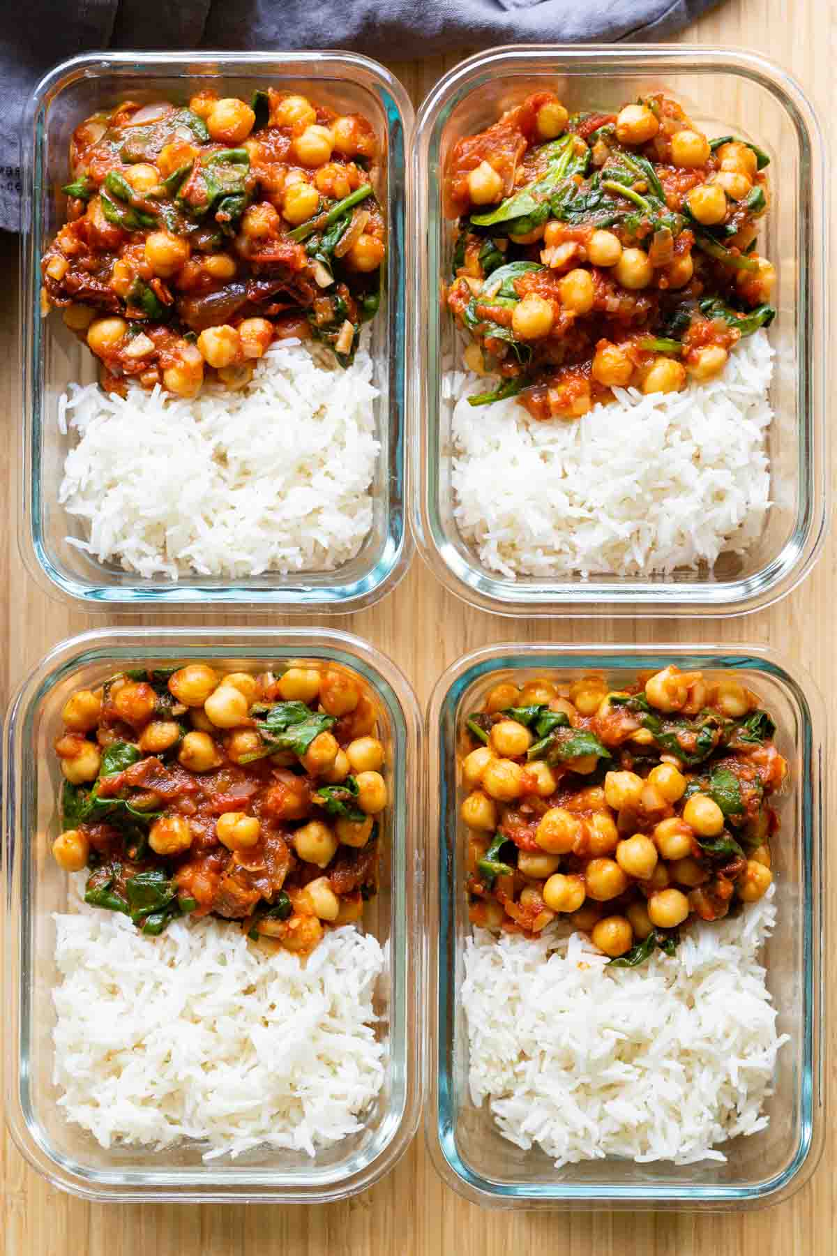 Four chipotle chickepe meal prep bowls next to each other showing white rice and chickpea stew.