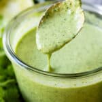 Aji Verde Sauce in a glass bowl with a golden spoon being dipped into it.